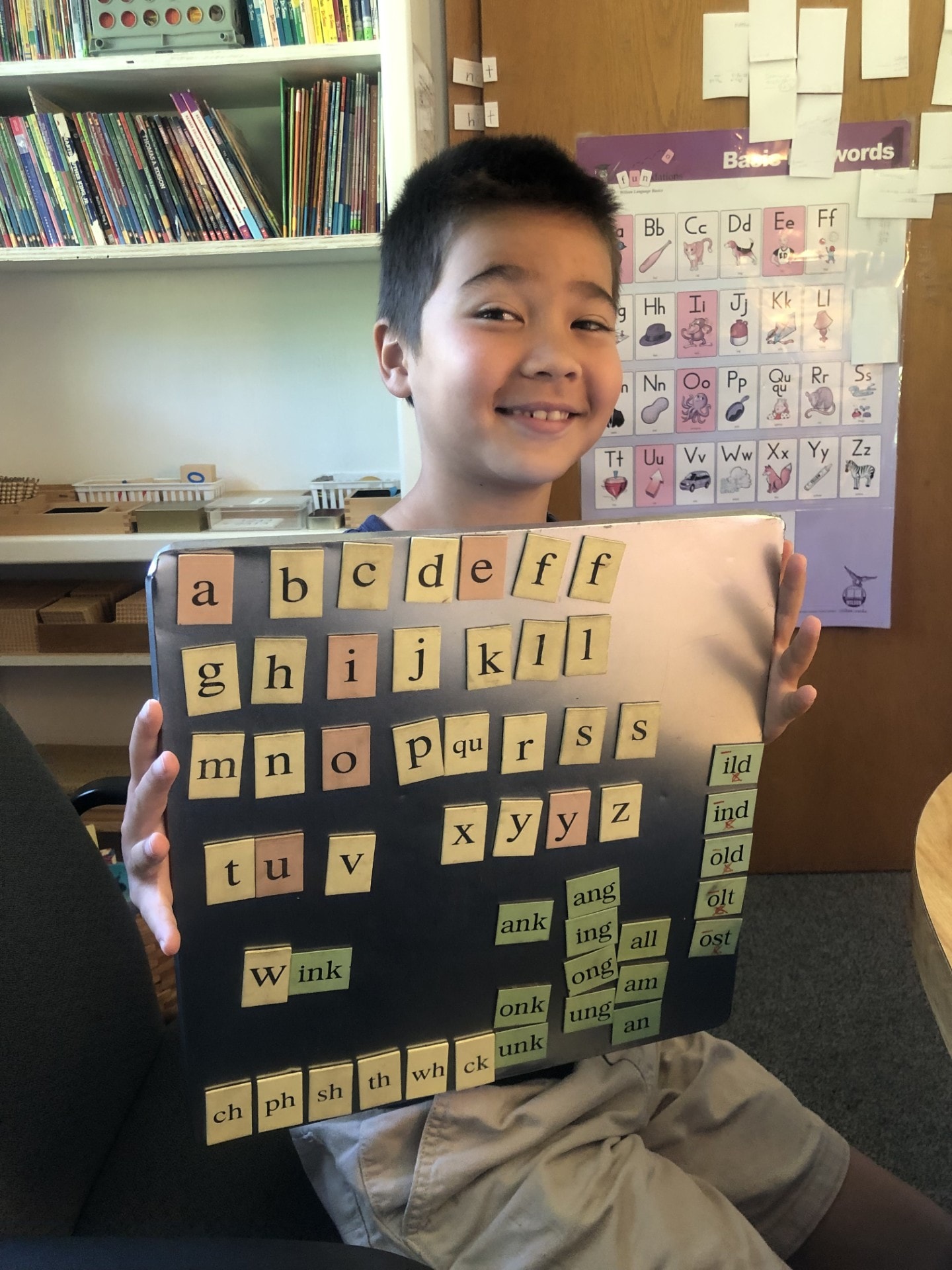 Student proudly holding his phonics letter board